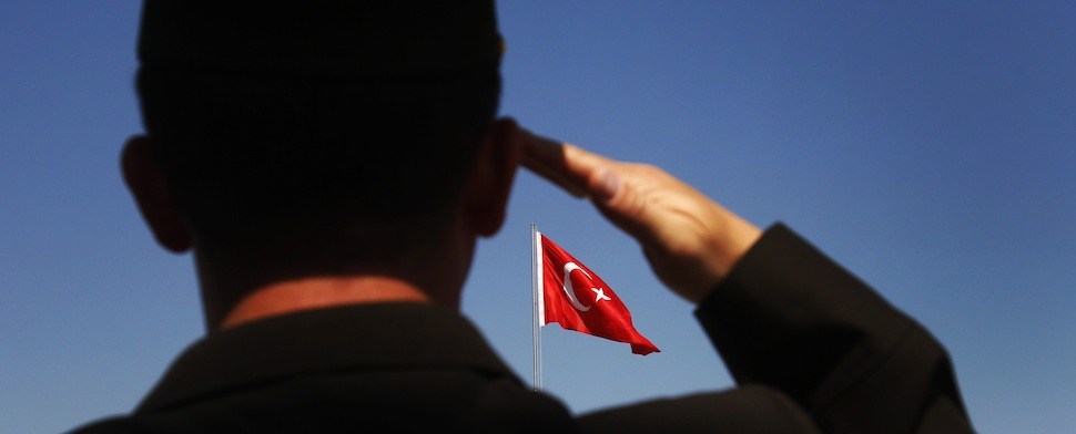 Ein türkischer Soldat salutiert vor einer türkischen Flagge.