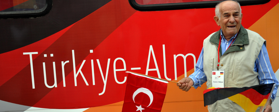 Ein älterer Mann, mit der türkischen Flagge und der deutschen Flagge vor dem "Deutschland-Zug" - (cihan)