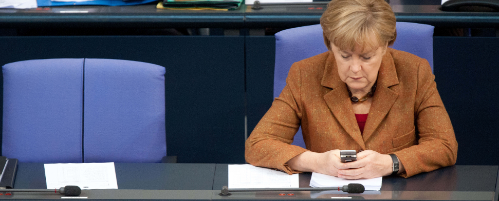 Bundeskanzlerin Angela Merkel (CDU) sitzt am 22.11.2012 im Reichstag in Berlin während einer Sitzung des Bundestags auf ihrem Platz und schaut auf ihr Mobiltelefon. Das Handy von Merkel ist möglicherweise von US-Geheimdiensten überwacht worden.