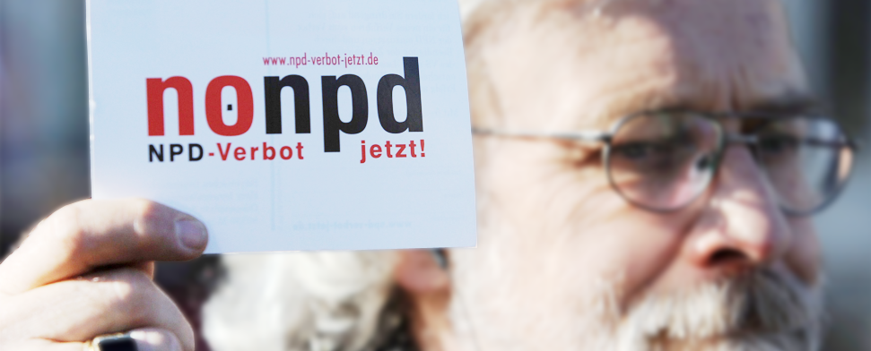 Ein Mann hält bei einer Demo einen Flyer mit der Aufschrift "no npd - NDP-Verbot jetzt" hoch. - rtr