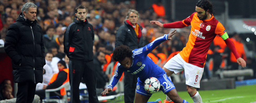 Selcuk Inan und Willian kämpfen im Spiel Galatasaray gegen Chelsea um den Ball. Mourinho und Mancini beobachten das Geschehen.