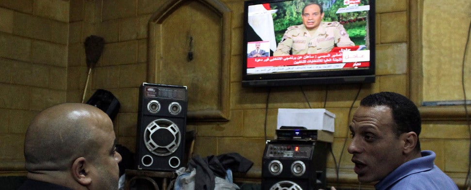 Zwei Männer in Kairo lauschen einer Fernsehansprache von al-Sisi.