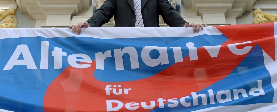 Der Bundesvorsitzende der Partei Alternative für Deutschland (AfD), Bernd Lucke, steht am 28.08.2013 auf einer Wahlkampfveranstaltung seiner Partei in Leipzig (Sachsen) auf einem Balkon mit dem Parteilogo.