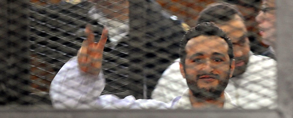 A file photo dated 22 December 2013 shows Egyptian activist Ahmed Douma flashing victory sign behind dock bars during his trial in Cairo, Egypt.