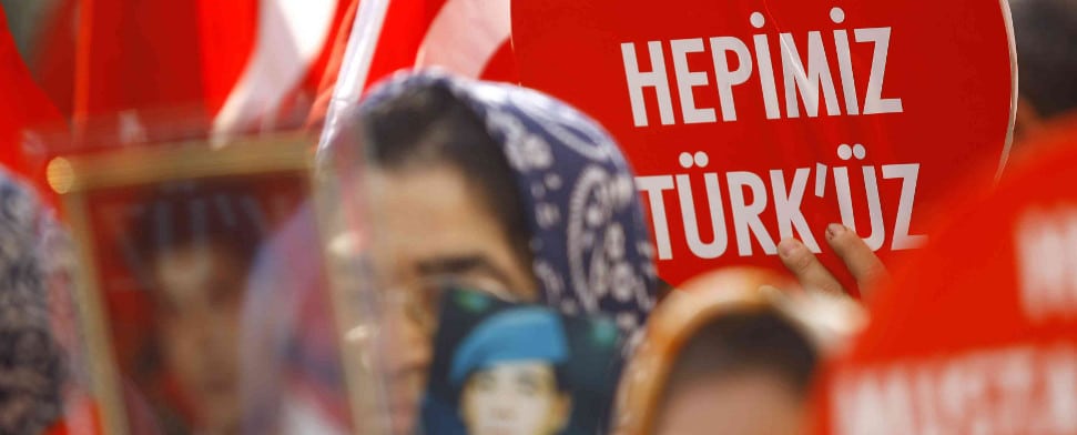 Eine Türkin hält ein Schild hoch, worauf "Wir sind alle Türken" zu lesen ist.