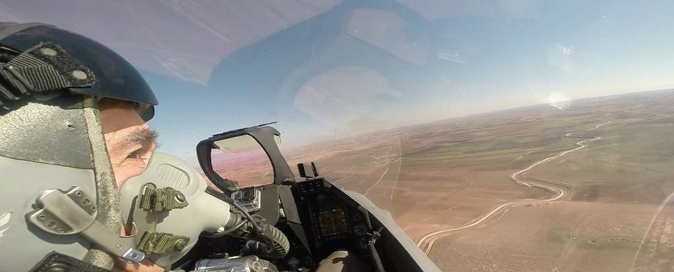 Das Innere eines Kampfjet-Cockpits über einer Wüstenlandschaft.