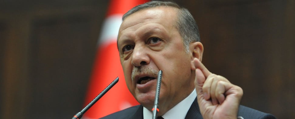 Recep Tayyip Erdogan redet am Mikrofon. Im Hintergrund die türkische Fahne zu erkennen.