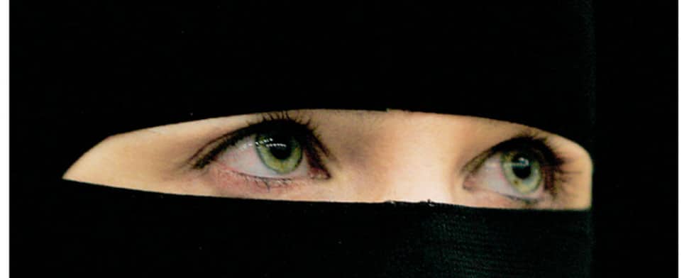 Eine Frau trägt einen schwarzen Niqab, der bis auf die Augen das gesamte Gesicht verdeckt.