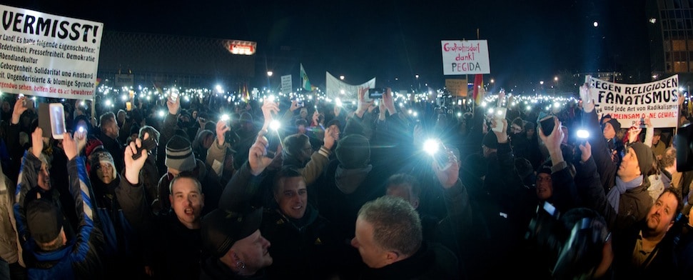 Teilnehmer einer Kundgebung der Pegida in Dresden (Sachsen) halten am 08.12.2014 zum Abschluss der Kundgebung leuchtende Mobiltelefone in die Höhe