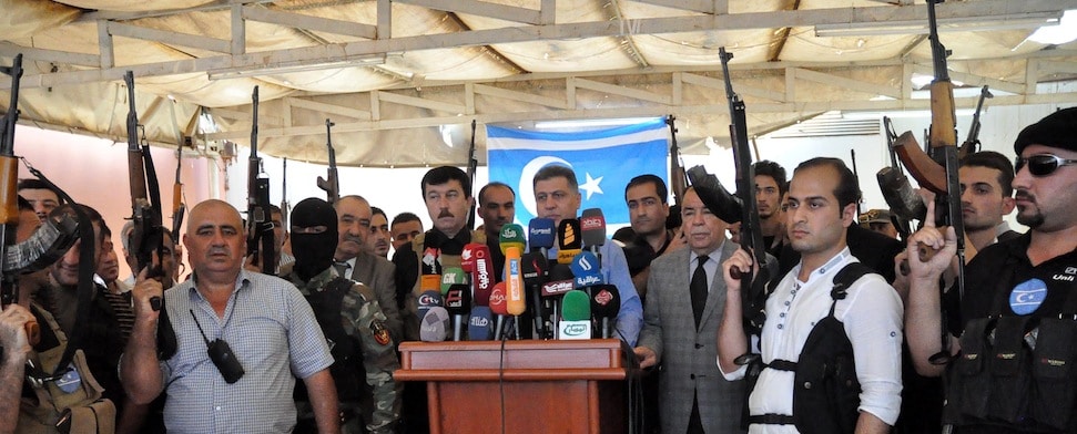 Bewaffnete Turkmenen stehen um ein Rednerpult ihres Anführers: Arshad al-Salihi, Vorsitzender der Turkmenenfront des Irak (Irak Türkmen Cephesi; kurz ITC)