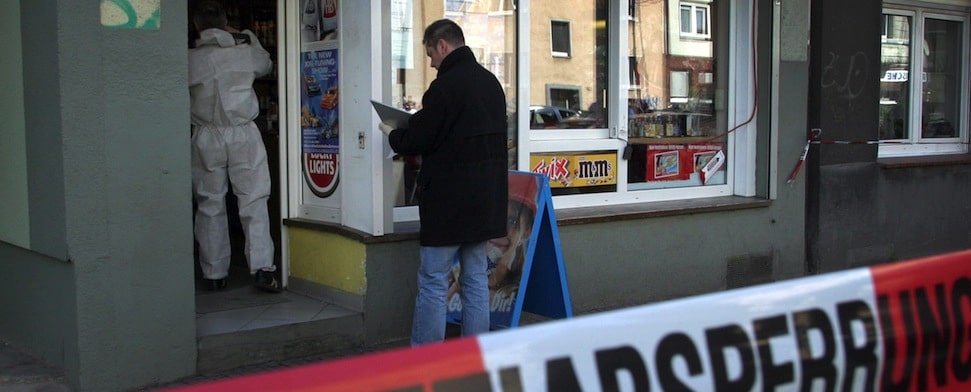 Polizeibeamte untersuchen nach einem Mord in Dortmund einen Kiosk auf Spuren