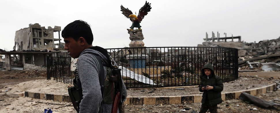 Das Zentrum von Kobane ist verwüstet. Ein junger Kämpfer der YPG läuft auf dem Azadiyya-Platz.
