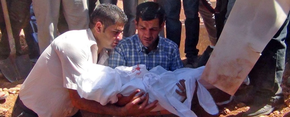 Zwei Männer halten den in ein weißes Leichentuch gehüllten Aylan Kurdi und heben ihn in sein Grab.